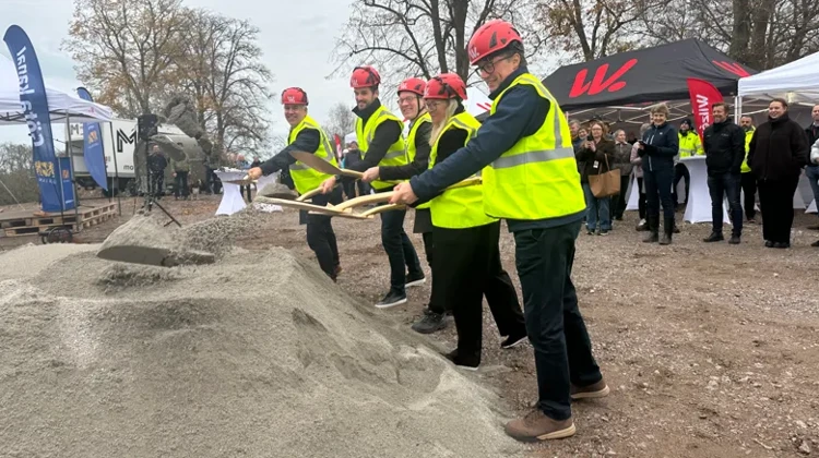 Fem personer har gul väst och hjälm på sig medan de tar ett spadtag och kastar jorden.